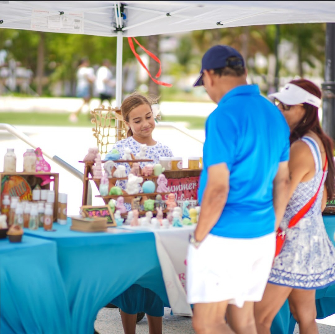 Customers browsing the Secret Glow Studio market booth